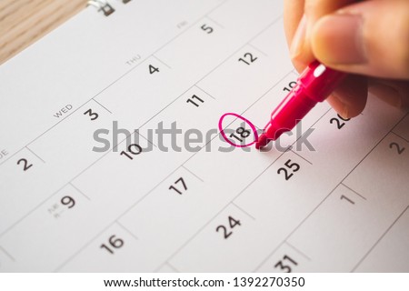 Female Hand with pen mark on calendar date Royalty-Free Stock Photo #1392270350