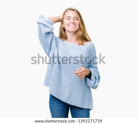 Beautiful young woman wearing blue sweater over isolated background Smiling confident touching hair with hand up gesture, posing attractive