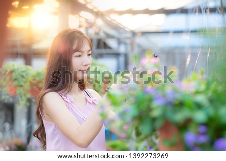 Asian beautyful woman use mobile phone photograph a flower blooming in garden on summer vacations