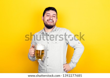 funny man with a glass of beer and foam on his mustache and nose over yellow background, party concept