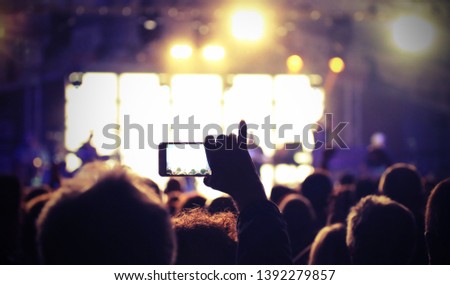 live concert and person of the audience that photographs the guitarist during the musical performance