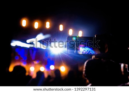 Picture of a lot of people enjoying night perfomance, large unrecognizable crowd dancing with raised up hands and mobile phones on concert. nightlife