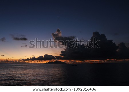 Early evening picture taken from the West coast of Mahe`, Seychelles, of Silhouette Island with cumulonimbus clouds and waxing moon above