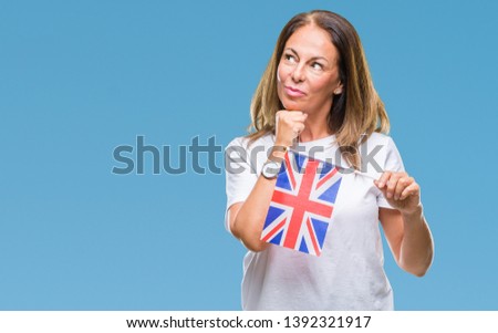 Middle age hispanic woman holding flag of United Kingdom over isolated background serious face thinking about question, very confused idea
