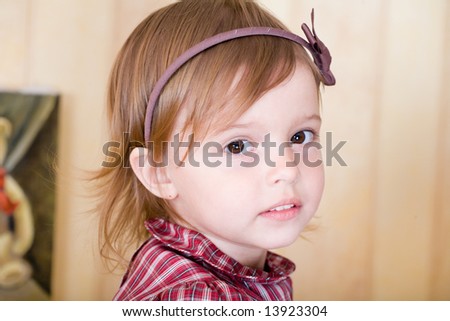 Portrait of a little girl with bow knot on head in living room