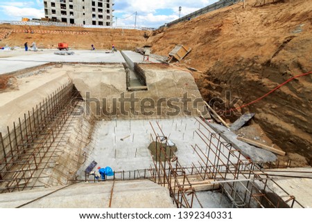 Ditch under construction of skyscraper or residential building with offices. Harvesting, screwing up piles. Pile driving. Construction site. Screw piles. Foundation (engineering).