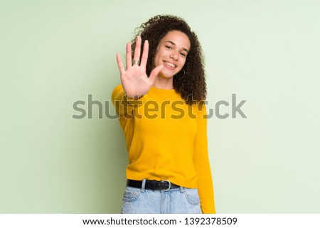 Dominican woman over isolated green background counting five with fingers