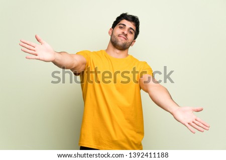 Young man over pink wall presenting and inviting to come with hand