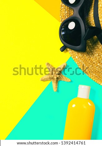 Beach accessories on a bright colorful background. A bottle of sunscreen lotion, dried starfish, a fragment of a straw hat and trendy black sunglasses . Summer vacation background.