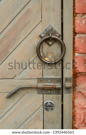 Old vintage door handle on a wooden door. The shutter is on the brown door. Round handle and open lock. Vertical photo