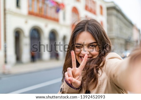 Pretty young woman taking selfie for social media while travel. Portrait of wonderful white female model with bright makeup expressing energy in good day in Europe.