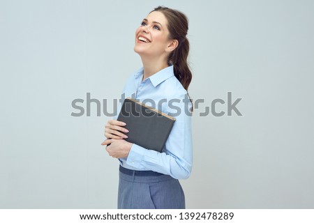 happy young woman with toothy smile looking up and holding book. Student or teacher isolated portrait.
