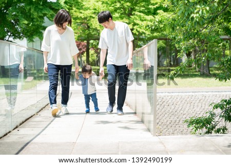 Family walking holding hands in park Royalty-Free Stock Photo #1392490199