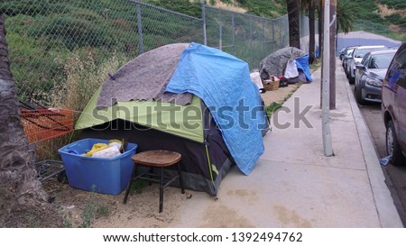 Homeless camp on a sidewalk in downtown Los Angeles, makeshift shelters made from tents and blankets. An issue that needs to be addressed.                               Royalty-Free Stock Photo #1392494762