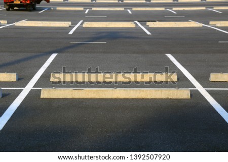 Empty parking stalls in a parking lot, marked with white lines. 