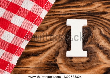 Letter I of the alphabet - Red checkered cloth tablecloth on rustic wood background