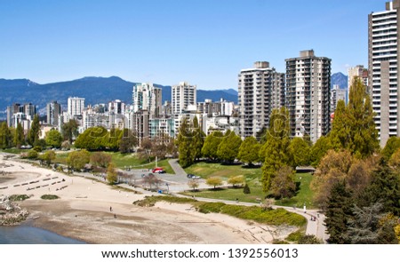 Wide shot of the multitude of appartments and condominiums that line Sunset Beach Park, in Vancouver with the Rockies rising in the background on a sunny day