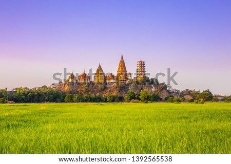 Landscape of Wat Tham Sua Temple (Tiger Cave Temple) in Sunset scence with Jasmine rice fields at Kanchanaburi Province, Thailand. Is an important landmark that everyone must visit