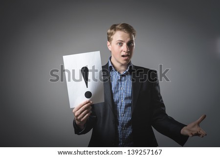 young businessman holding a sheet with exclamation mark on it