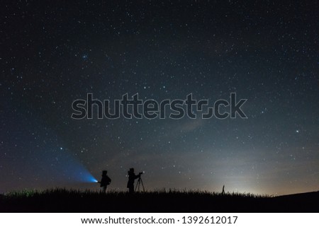 Silhouette photographers with a sky full of stars background at night