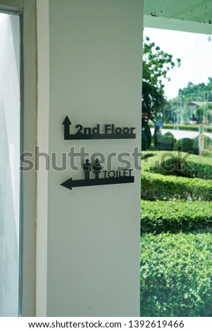 Toilet and 2nd second floor directional sign on white wall