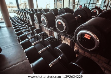 Photo of many different dumbbells in modern sunny gym.