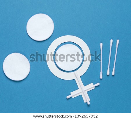 Products for feminine hygiene, self-care and health, female gender symbol on blue background. Ear sticks, pads. Top view