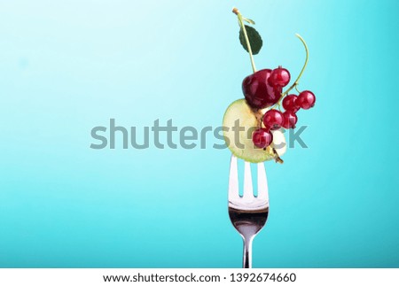 cherry on silver fork against a blue background concept for healthy eating, dieting and antioxidant. Summer,  pattern Flying copy space