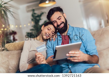 Smiling couple using digital tablet and credit card at home Royalty-Free Stock Photo #1392721163