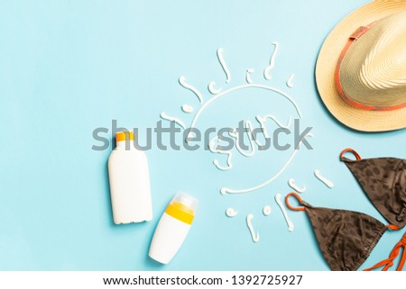 Summer beach accessories sunscreen hat swimsuit bright blue background text SUN. The concept of relaxation the beach.