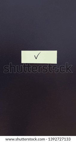 sticky note on black board - check mark
