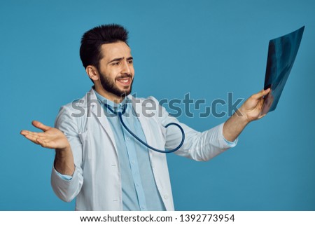  smiling doctor looking at x-ray on a blue background                              