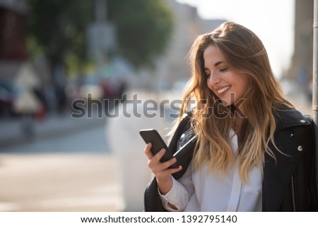 Happy young teenage girl holding phone, bokeh effect.