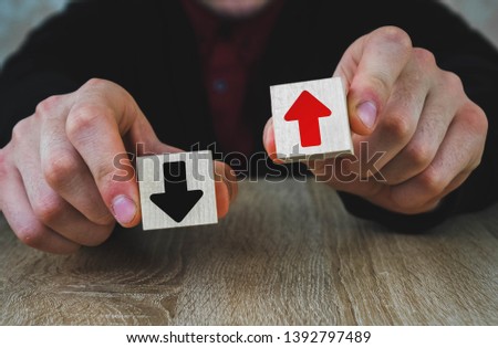 two wooden cubes in the hands of a man of red and black, red means growth and development, and black arrow means fall and degradation, extinction, regression