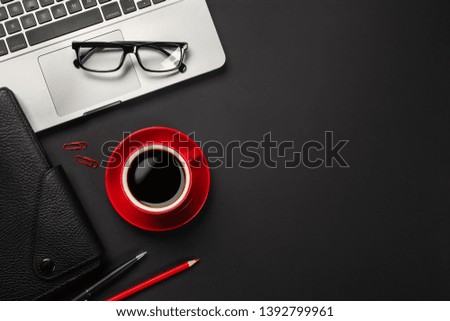 Black office desk table with blank screen laptop computer, notebook, mouse, cup of coffee and other office.Top view with copy space