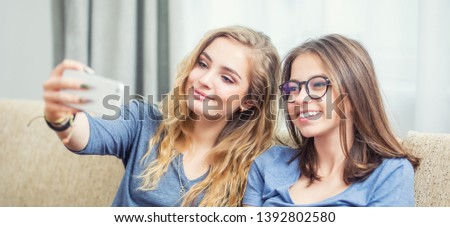 Two teen girls smile and take a selfie together.