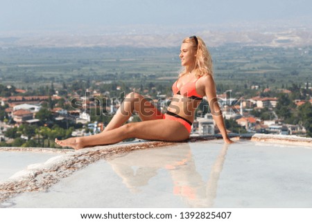 A young girl is sitting on the edge of the travertine, sunbathing. Pamukkale Turkey