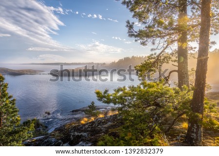 Foggy landscape of northern nature. Magnetic sunny view of the islands and fjords. Awesome sunrise on the lake. Ladoga lake. Smoky summer landscape. Primeval Russia. Archipelago. Republic Karelia.