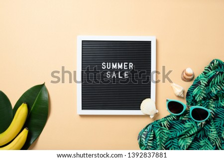 Women's beach accessories: straw hat, sunglasses, green scarf, banana and letter board with sign "SUMMER SALE" on yellow background. Summer sale banner template concept. Flat lay composition, top view