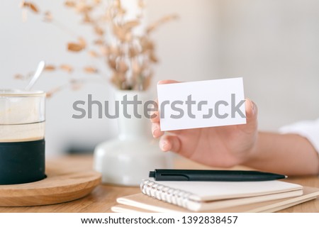 A hand holding and showing white empty business card 