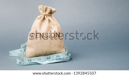 Money bag with the word Pension and tape measure. Fall / reduction pension payments. Retirement. Financing retirees. Reduction of the pension fund. The low size of pensions. Poverty. Lack of money Royalty-Free Stock Photo #1392845507