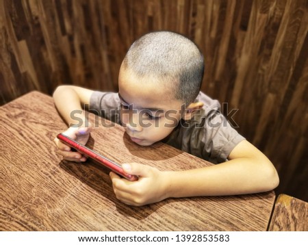 Young boy holding and watching movie on smartphone