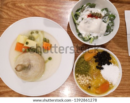 Photo of a very healthy menu consisting of 3 dishes - boiled vegetables on the plate to the left, a green salad with yogurt on the top-right of the picture, and a peach desert on the bottom-right.
