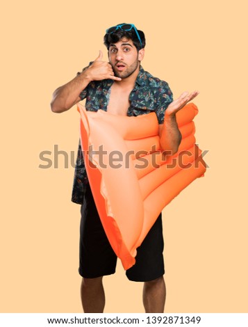 Man in trunks making phone gesture and doubting over isolated yellow background