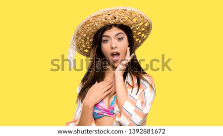 Teenager girl on summer vacation surprised and shocked while looking right over isolated yellow background