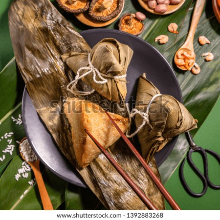 Zongzi, woman eating steamed rice dumplings on green table background, food in dragon boat festival duanwu concept, close up, copy space, top view, flat lay