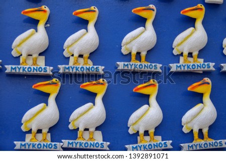 Identical fridge magnet souvenirs of Petros the Pelican on blue background merchandise for sale to Mykonos Island tourists on summer holidays in the Greek Islands with tourist boosting the economy.  