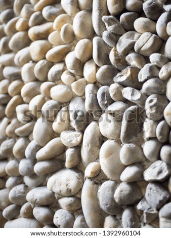 Wall decorated with round natural stones. Stone texture and background concept.