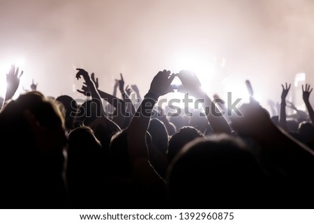 Crowd with raised hands and smartphone record a concert