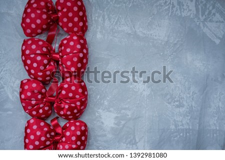 Red polka dot bows. Plush bow A toy. Light background under the concrete. Space for text.
